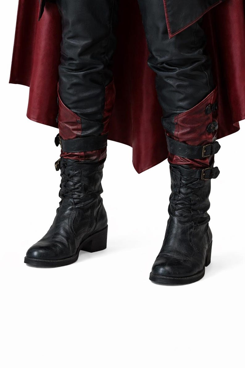 K&ouml;nnte beinhalten: Schwarze Lederstiefel mit Blockabsatz. Die Stiefel haben einen dekorativen Riemen mit Schnallen und einen roten Lederakzent. Die Stiefel werden mit einer schwarzen Lederhose und einem roten Umhang kombiniert.