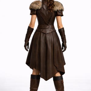 May include: A brown leather dress with fur shoulder accents, short sleeves, and a flared skirt. The dress features intricate detailing on the bodice and belt, with matching gloves and knee-high boots. The outfit is designed with a medieval or fantasy theme.
