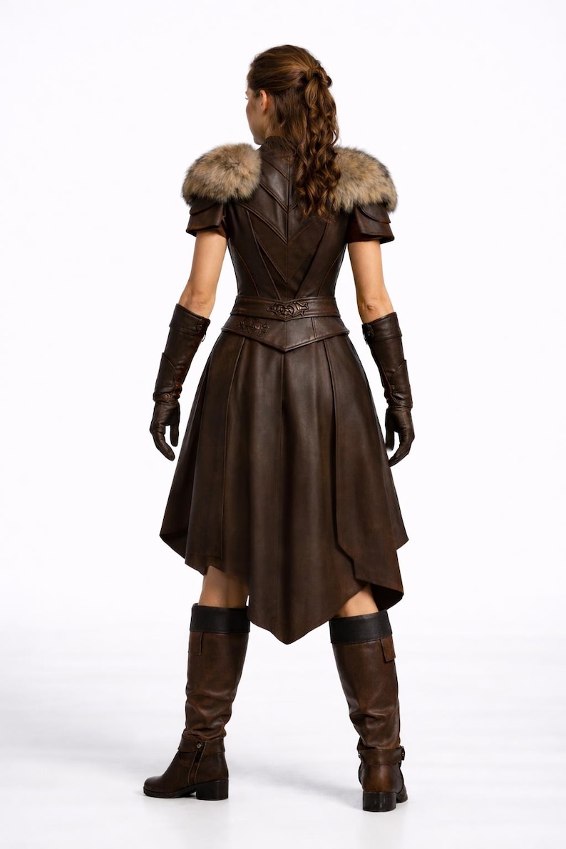 May include: A brown leather dress with fur shoulder accents, short sleeves, and a flared skirt. The dress features intricate detailing on the bodice and belt, with matching gloves and knee-high boots. The outfit is designed with a medieval or fantasy theme.