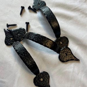 Può includere: Maniglie per porte in ferro battuto nero con finitura strutturata e dettagli a forma di cuore. Include quattro viti abbinate per l'installazione. Le maniglie hanno un design curvo e sono adatte per armadi o porte.