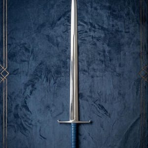 Op de afbeelding: Een lang, zilveren zwaard met een punt en een blauw lederen handvat. Het zwaard heeft een pareerstang en een decoratieve pommel. De achtergrond is een donkerblauwe fluwelen stof met een gouden geometrische rand.
