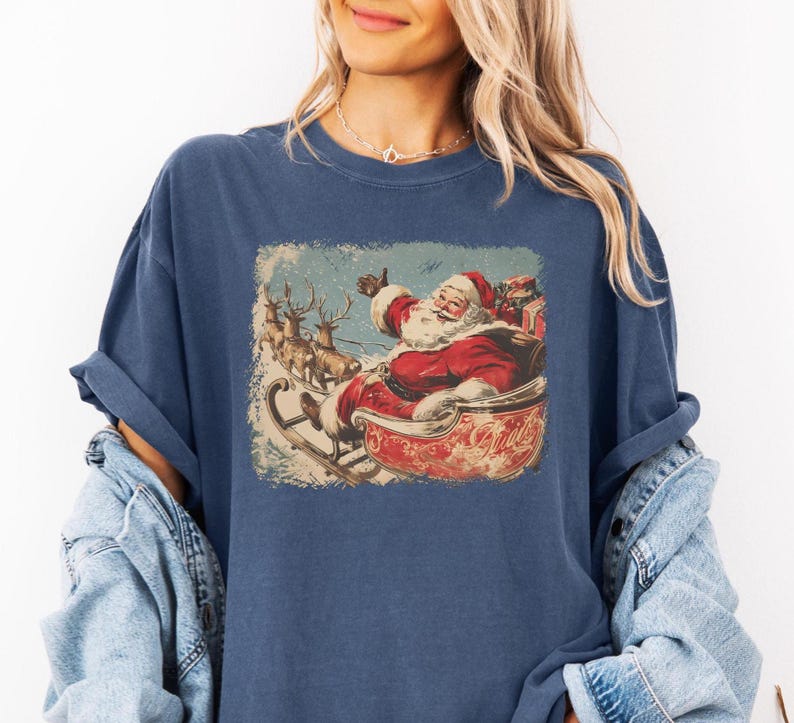 blue Christmas comfort colors shirt with vintage 60s Santa Claus riding sleigh and reindeer illustration; retro Santa Christmas tee, classic holiday t-shirt, cozy winter top, nostalgic Christmas graphic design, unisex festive crewneck, holiday gift idea, traditional Christmas aesthetic sweatshirt, matching family Christmas outfits sweater.