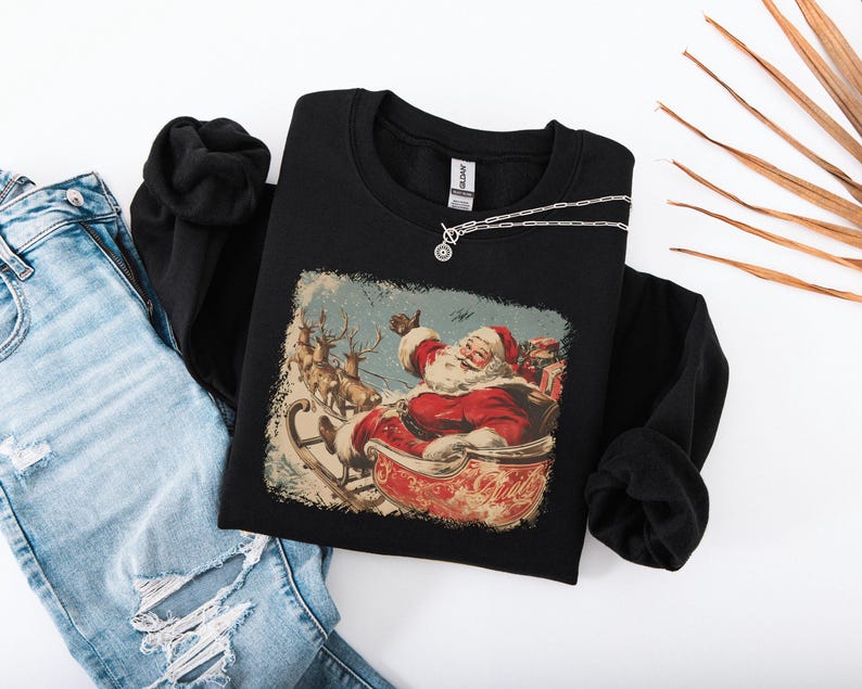 black Christmas sweatshirt with vintage 60s Santa Claus riding sleigh and reindeer illustration; retro Santa Christmas sweater, classic holiday sweatshirt, cozy winter pullover, nostalgic Christmas design, unisex festive apparel, holiday gift idea, traditional Christmas aesthetic sweatshirt, matching family Christmas outfits.