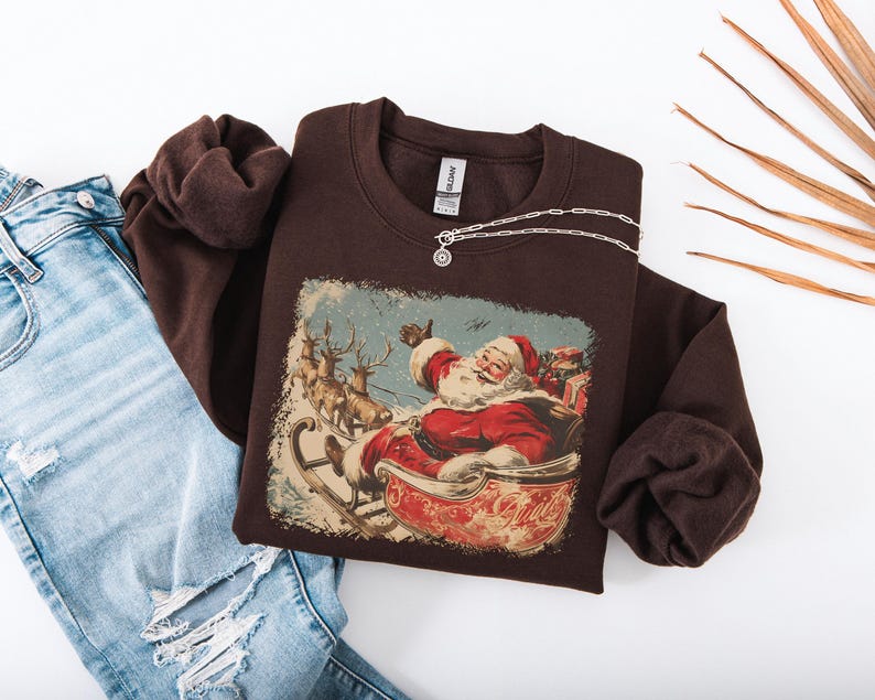 brown Christmas sweatshirt with vintage 60s Santa Claus riding sleigh and reindeer illustration; retro Santa Christmas sweater, classic holiday sweatshirt, cozy winter pullover, nostalgic Christmas design, unisex festive apparel, holiday gift idea, traditional Christmas aesthetic sweatshirt, matching family Christmas outfits.