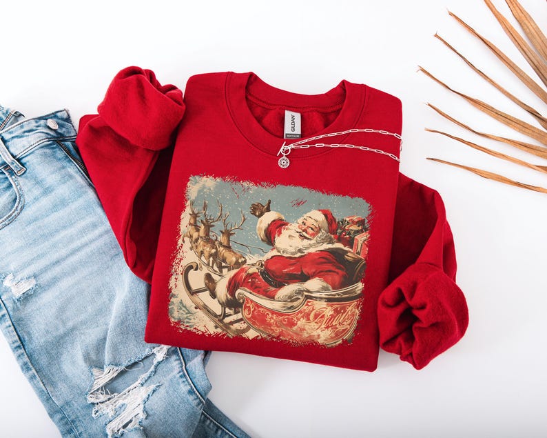 red Christmas sweatshirt with vintage 60s Santa Claus riding sleigh and reindeer illustration; retro Santa Christmas sweater, classic holiday sweatshirt, cozy winter pullover, nostalgic Christmas design, unisex festive apparel, holiday gift idea, traditional Christmas aesthetic sweatshirt, matching family Christmas outfits.