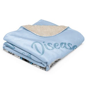 Pu&ograve; includere: Una coperta in pile sherpa azzurro piegata con un lato inferiore testurizzato color crema. La superficie superiore presenta una stampa grafica parziale con la parola Disease scritta in un carattere corsivo blu scuro e un'illustrazione in bianco e nero.