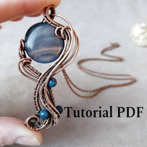 Könnte beinhalten: Kupferdraht-Anhänger mit einem großen, runden, blau-grauen Stein und kleineren blauen Perlen. Der Anhänger hängt an einer filigranen Kupferkette. Der Text "Tutorial PDF" ist im Bild zu sehen.