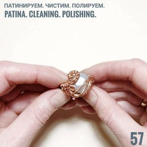 Peut inclure: Une bague en fil de cuivre faite &agrave; la main avec une pierre ronde de couleur claire. La bague est tenue entre deux mains. Le texte "PATINA. CLEANING. POLISHING." est en haut, et le num&eacute;ro "57" en bas &agrave; droite.