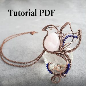May include: A handmade copper wire pendant featuring a rose quartz stone and blue bead detailing. The pendant hangs from a copper chain. The image includes the text "Tutorial PDF" at the top.