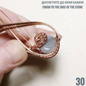 Peut inclure: Un pendentif artisanal en fil de cuivre avec une pierre bleu clair. Le fil est finement tiss&eacute; autour de la pierre, formant une cage d&eacute;corative. Le texte "FINISH TO THE EDGE OF THE STONE" est visible en haut, et le chiffre "30" en bas.