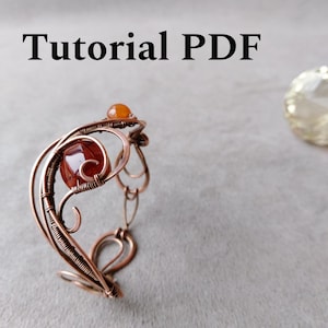 May include: A copper wire bracelet with a swirling design, featuring a large, square, orange-red gemstone and a smaller, round, orange gemstone. The text "Tutorial PDF" is at the top.