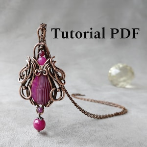 May include: A handcrafted copper wire pendant with a large, striped magenta stone at its center. The pendant features intricate wirework and is accented with smaller magenta beads. The text "Tutorial PDF" is displayed in black.