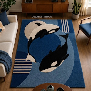 Puede incluir: Una alfombra rectangular con fondo azul y dos orcas dispuestas en círculo. El diseño incluye rayas geométricas y el texto OCEAN ART RUGS. La alfombra presenta tonos azul marino, azul claro, negro y crema.