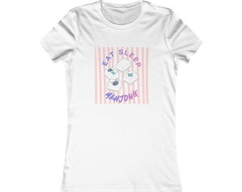 May include: White t-shirt featuring a graphic with the words "EAT SLEEP MAH JONG" in a playful font. The design includes stylized Mahjong tiles on a pink and white striped background. A casual, comfortable tee.