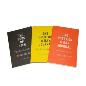 Può includere: Tre diari con copertine di colori diversi. Il diario nero recita "THE BOOK OF LIFE". Il diario giallo recita "ONE QUESTION A DAY JOURNAL". Il diario arancione recita "ONE QUESTION A DAY JOURNAL".