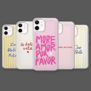 Op de afbeelding: Een verzameling telefoonhoesjes met verschillende ontwerpen en tekst. Eén hoesje heeft de woorden "MORE AMOR POR FAVOR" in roze, een andere zegt "la dolce vita" in rood, en andere hebben zinnen in blauw en geel.