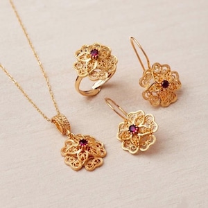 Set di gioielli in argento sterling 925 placcato oro con rubini e motivi floreali: collana, anello e orecchini.