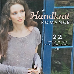May include: A softcover book titled A Handknit Romance with the subtitle 22 Vintage Designs with Lovely Details by Jennie Atkinson. The cover features a person wearing a light gray knit top and matching fingerless gloves with beaded accents.