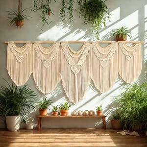 May include: Five cream-colored macrame wall hangings with intricate woven patterns and fringe, suspended from a wooden rod. The wall hangings are displayed against a light blue wall, with various potted plants and a wooden bench in the foreground.