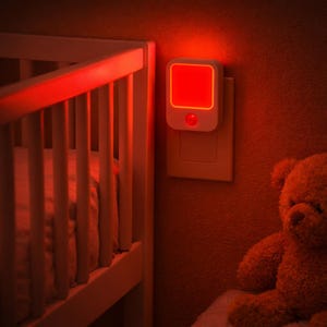 May include: A white night light with a red glowing square is plugged into a wall outlet. The night light is next to a white crib and a brown teddy bear. The room is lit with a soft red glow.