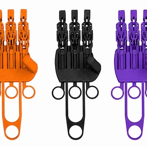 May include: Three articulated mechanical hand devices in orange, black, and purple. Each device features a palm section with three jointed finger segments, a thumb, and a lower frame with three circular finger loops and one large base loop.