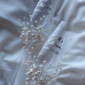 Puede incluir: Dos copas de champ&aacute;n con texto plateado "Mrs. Elatanov September 2020" y "Mr. Elatanov September 2020". Cada copa est&aacute; adornada con un delicado arreglo de perlas y cristales, creando un elegante tema de boda.