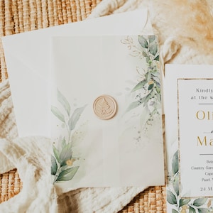 Puede incluir: Elegante conjunto de invitaciones de boda con sobre y tarjeta blancos. La tarjeta está adornada con vegetación de acuarela y detalles dorados, sellada con un sello de cera beige. El diseño incluye elementos botánicos y una fuente clásica.