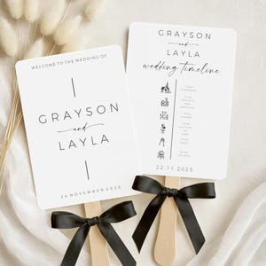 May include: Two white wedding fans with black text and black ribbon bows. One fan reads "Welcome to the Wedding of Grayson and Layla" and the date. The other fan displays a wedding timeline with icons and the date.