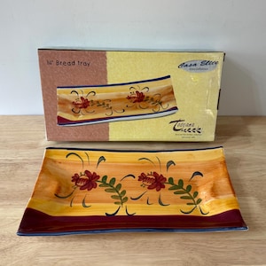 May include: Rectangular bread tray, 35.5 cm long, with a hand-painted floral design. The tray features a yellow and orange background with burgundy and blue accents. The box reads "Casa Elite" and "Toscana Collection."