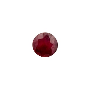 May include: A faceted, round-cut ruby gemstone. The gem is a deep, rich red color with visible internal facets. The ruby is set against a plain white background, highlighting its color and cut.