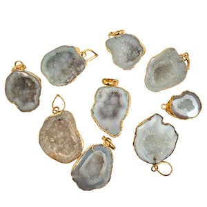May include: A collection of geode pendants with gold-colored metal edging and bails. The pendants have a natural, irregular shape with a light gray and white crystal interior. The gold-colored metal adds a touch of elegance to the natural stone.