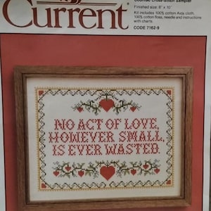Puede incluir: Un kit de punto de cruz contado enmarcado con el texto "NO ACT OF LOVE, HOWEVER SMALL, IS EVER WASTED". El tamaño final es de 20 x 25 cm. El diseño incluye corazones rojos y detalles florales.