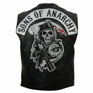 May include: Black leather vest featuring a large patch on the back with the words "SONS OF ANARCHY" in white lettering. The patch depicts a skull holding a scythe, with a red blood-like design. The vest is sleeveless.