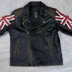 May include: Black leather motorcycle jacket with a diagonal zipper and Union Jack flag design on the sleeves. The jacket features quilted shoulder and sleeve detailing, and a distressed finish.