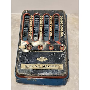 May include: Vintage Wolverine Adding Machine with a blue and black metal case. The machine has five columns of number sliders and displays the total as 2078. The text "Adding Machine" and "Patent Pending" are visible.