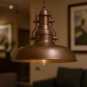 Op de afbeelding: Een bronzen hanglamp met een koepelvormige kap en een zichtbare gloeilamp. Het licht hangt aan een ketting en heeft decoratieve details. De lamp is ontworpen in een vintage industriële stijl, geschikt voor woondecoratie.