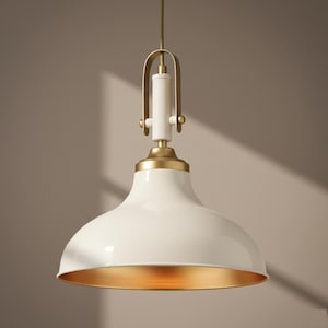 May include: A white pendant light with a gold interior and brass accents. The light fixture has a rounded, bell-shaped shade and a gold-colored interior. The hanging hardware is brass and white.