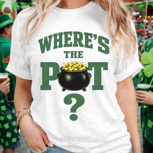 May include: White t-shirt with the text "WHERE'S THE POT?" in green. The "POT" is a black cauldron filled with gold coins, and a green question mark is below. The shirt is likely for St. Patrick's Day.