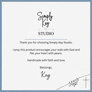 May include: A light blue card with the text "Simply Kay Studio" in elegant script. The card includes a message of faith and love, with the words "Jesus loves you" and a cross symbol.
