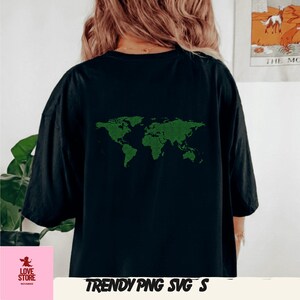 Op de afbeelding: Zwart T-shirt met een groen, gepixeld wereldkaartontwerp op de achterkant. Het shirt heeft korte mouwen en een relaxte pasvorm. De tekst "TRENDY PNG SVG'S" staat onderaan de afbeelding. Het Love Store-logo staat linksonder.