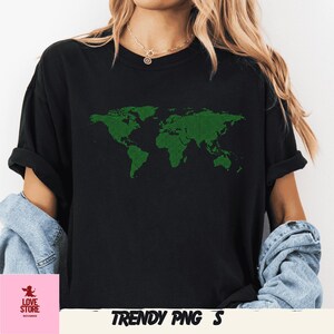 Op de afbeelding: Zwart T-shirt met een groen, gepixeld wereldkaartontwerp. Het shirt heeft korte mouwen en een losse pasvorm. De tekst "TRENDY PNG S" staat onderaan het shirt.