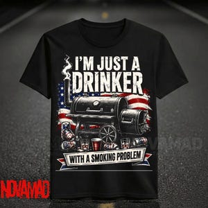 May include: A black t-shirt featuring a graphic of a barbecue smoker with smoke rising, set against a stylized American flag. The text reads I'M JUST A DRINKER WITH A SMOKING PROBLEM, accompanied by illustrations of beverage cans and red plastic cups.