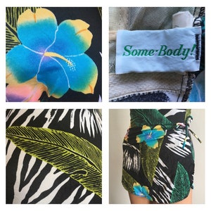 Pode incluir: Saia envelope preta com estampa floral tropical, flores de hibisco azuis e amarelas, folhas verdes e padr&atilde;o de zebra. Fechamento com la&ccedil;o. A etiqueta diz "Some-Body!"