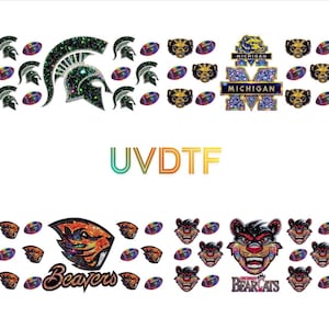 May include: A sheet of UV DTF decals featuring various sports team logos and football graphics. The designs include a Spartan helmet, Michigan block M, a beaver mascot, and a Bearcats mascot, all rendered with a glittery, holographic finish.
