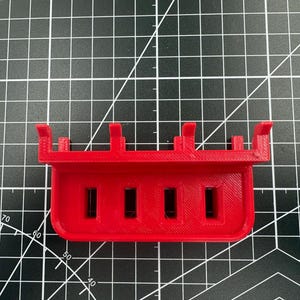 Top-down view of a red USB drive holder showing the four precision-milled 12.50mm by 5mm slots designed to keep drives upright.