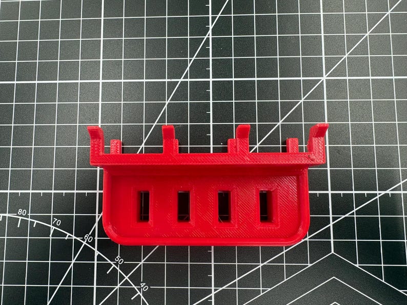 Top-down view of a red USB drive holder showing the four precision-milled 12.50mm by 5mm slots designed to keep drives upright.