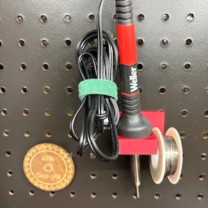 Red high-strength PETG soldering station mounted on a standard 1-inch pegboard showing a secure fit.