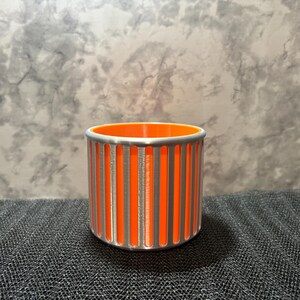 A high-contrast silver and orange 3D printed pencil holder with a beveled base, perfect for a cyberpunk-themed desk setup.