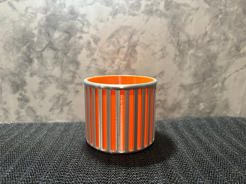 A high-contrast silver and orange 3D printed pencil holder with a beveled base, perfect for a cyberpunk-themed desk setup.