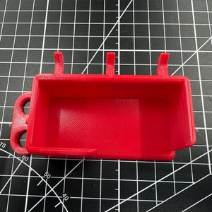 Top-down view of the red multimeter holder on a grid mat, highlighting the spacious internal storage area and integrated probe management loops.